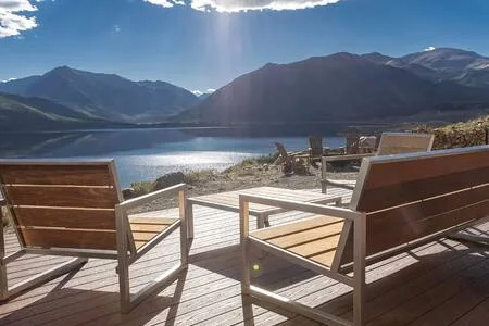 Deck chairs overlooking bright lake and mountain range