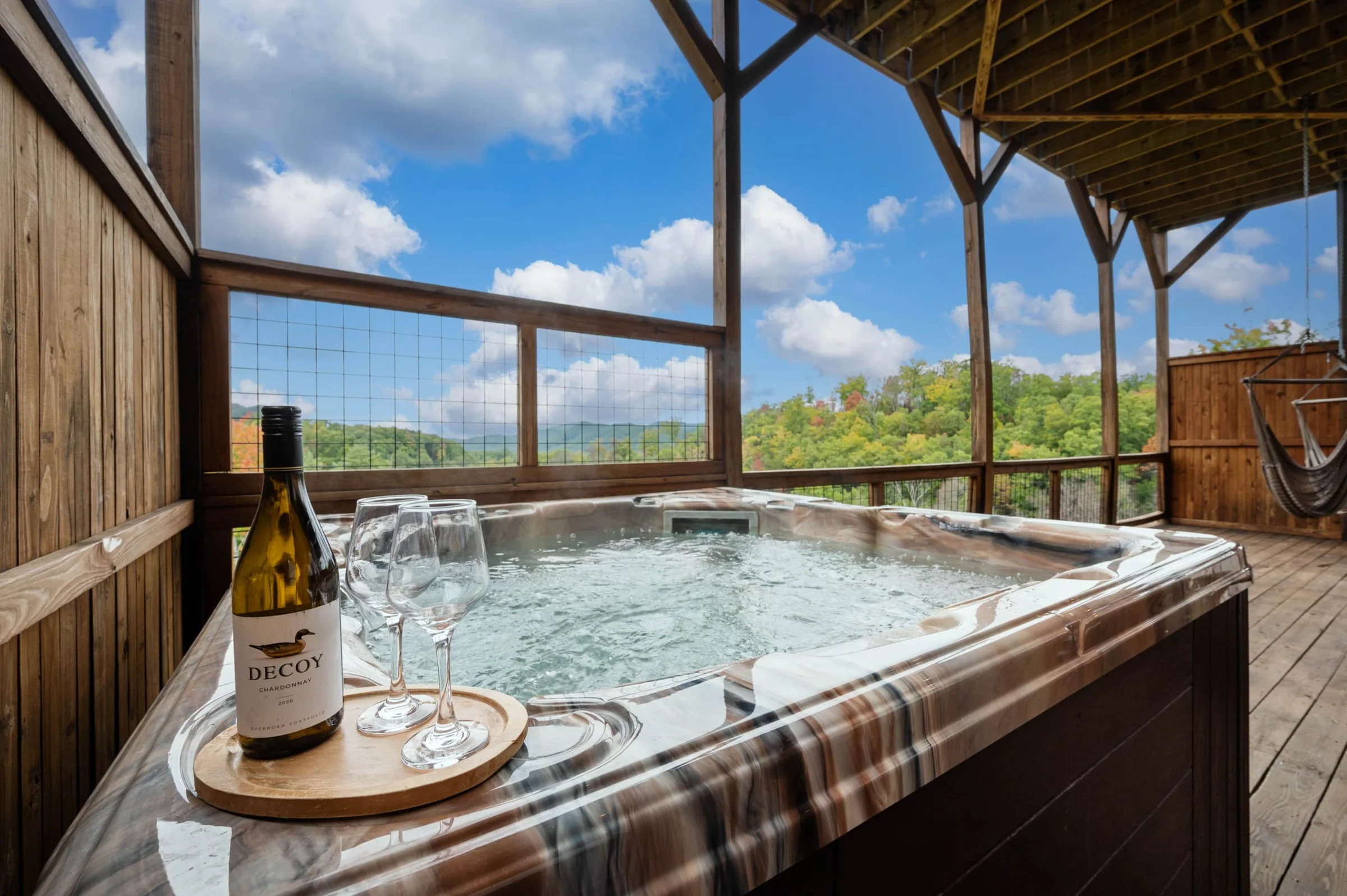 Covered deck hot tub with mountain view and wine