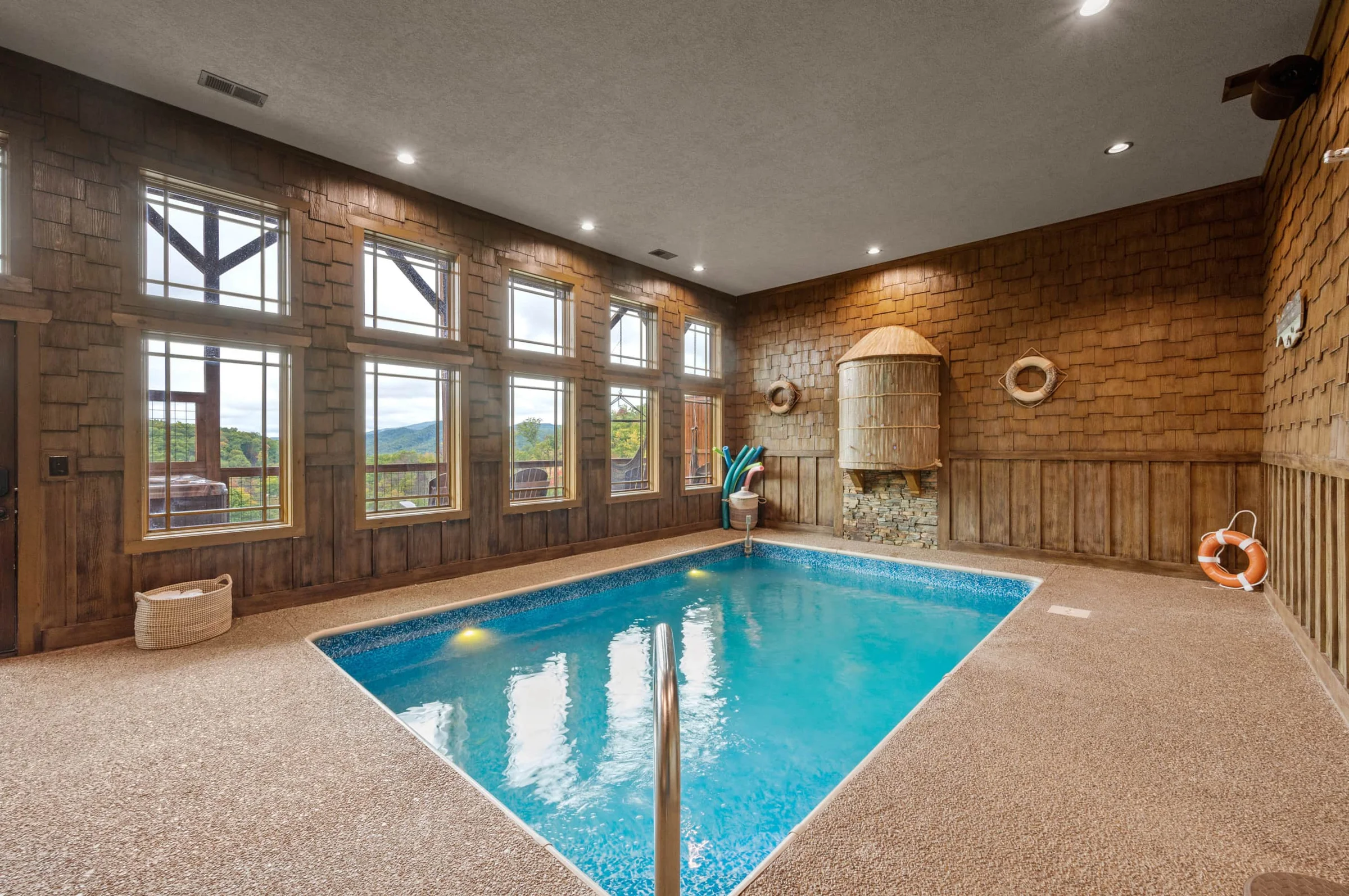 Indoor pool room with large windows and mountain views